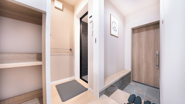 A modern hotel room with a wooden floor, a grey exercise mat, a wooden door, and a framed peace sign on the wall. - TEN6-TenSix- (Osaka)