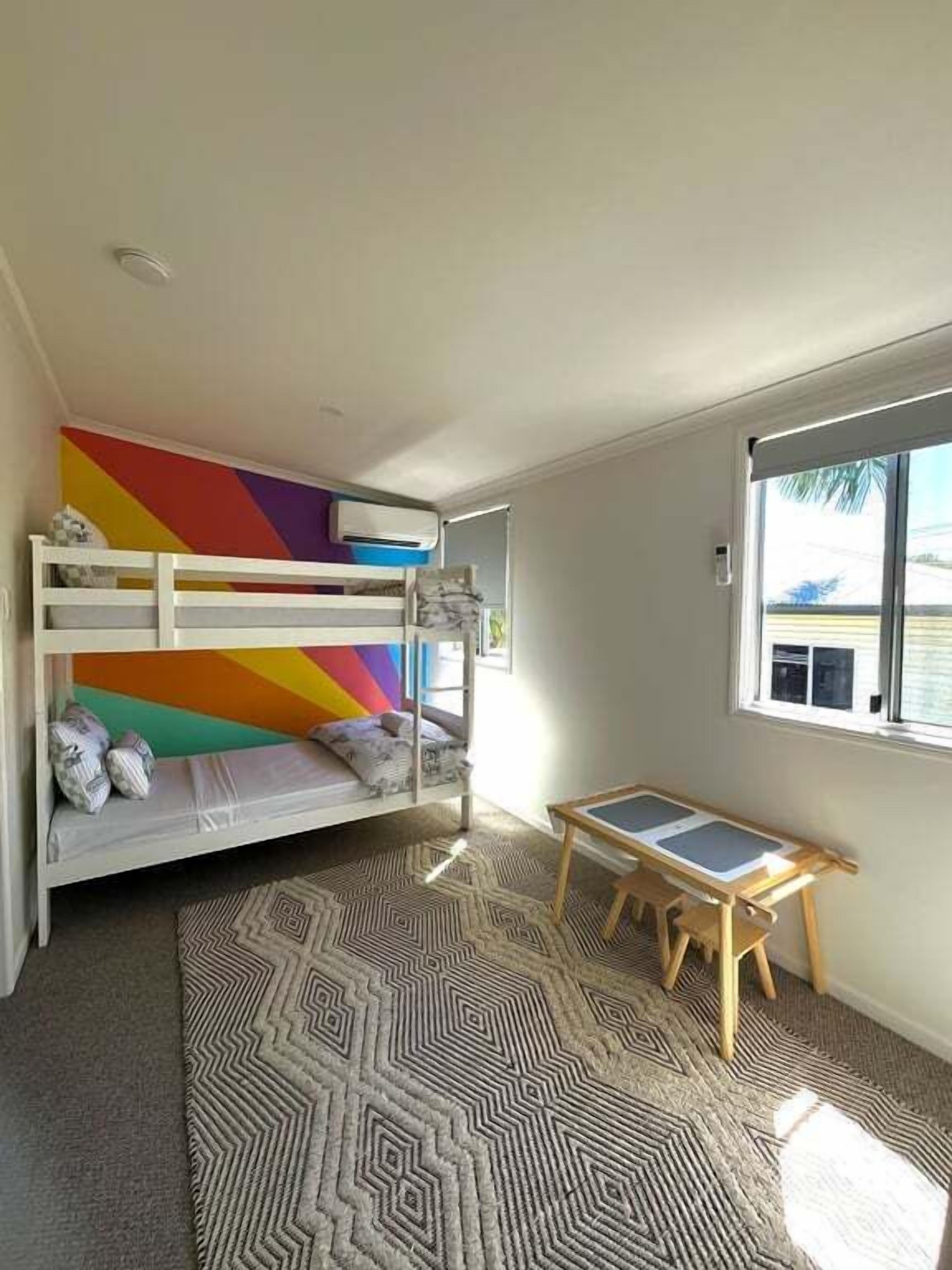 Una cama individual superpuesta con un diseño de pared colorido, una mesita pequeña y una alfombra estampada.