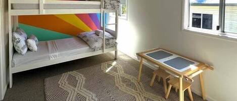 Una cama individual superpuesta con un diseño de pared colorido, una mesita pequeña y una alfombra estampada.