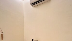 A small, modern room with a desk, chair, and an air conditioning unit mounted on the wall. - ONE18 Boutique Hotel - Kuala Lumpur (Kuala Lumpur)