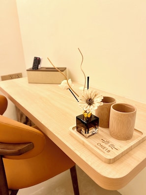Ein Holztisch mit einer Blumenvase, einer Fernbedienung und zwei hölzernen Tassen.