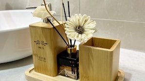 A bathroom with a wooden soap dish holding a white flower, a black soap dispenser, and a wooden container with a label. - ONE18 Boutique Hotel - Kuala Lumpur (Kuala Lumpur)