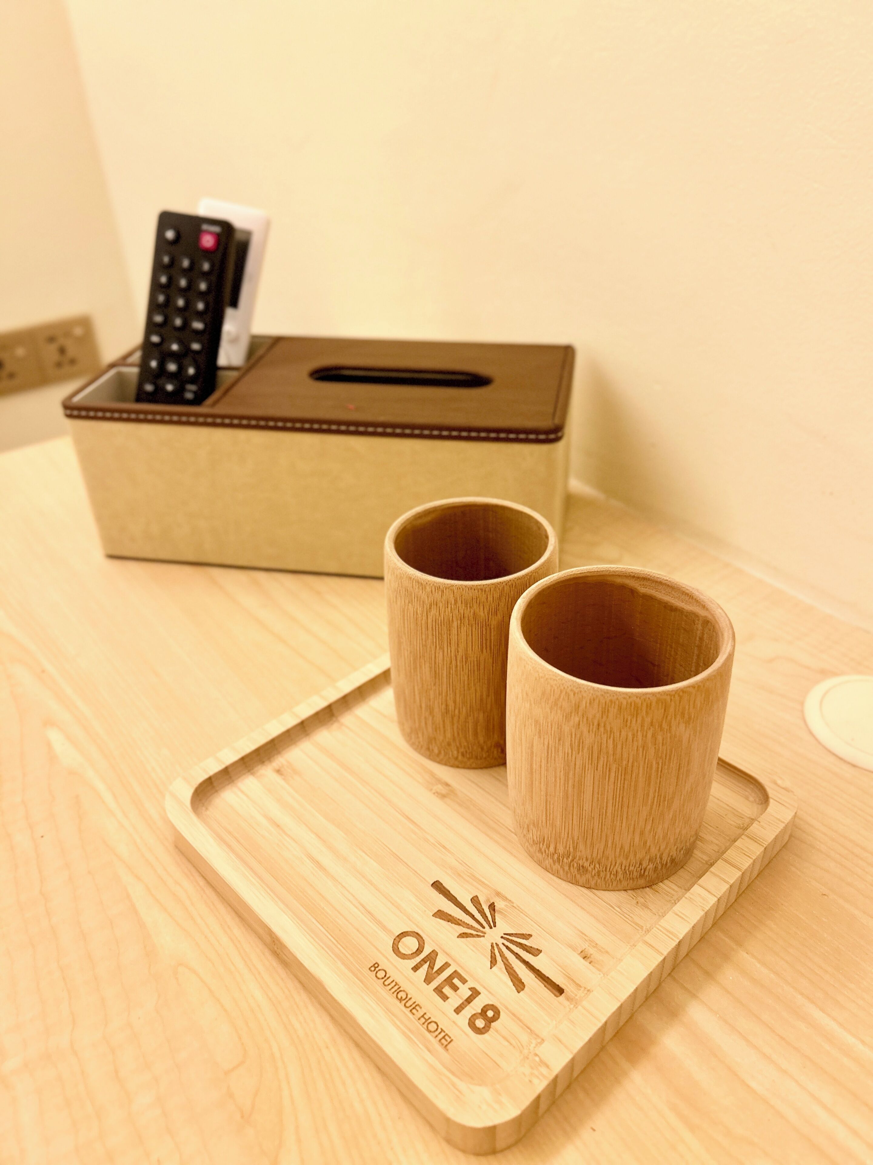 Un plateau en bois avec deux tasses et une boîte contenant une télécommande.
