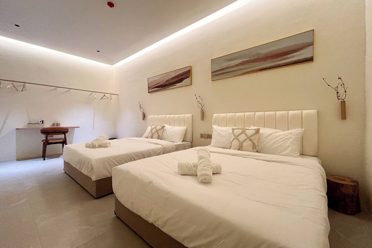 A hotel room with two beds, a desk, and artwork on the walls.
