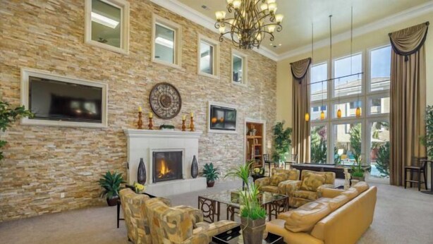 A spacious living room with a stone wall, fireplace, comfortable seating, and large windows. - New Trendy 1BR Apartment with Heated Pool, Gym & Minigolf (Reno)