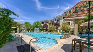 A pool area with lounge chairs, a hot tub, and umbrellas. - New Trendy 1BR Apartment with Heated Pool, Gym & Minigolf (Reno)