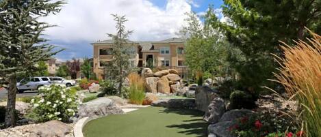 A landscaped area with a pool, rocks, and a building in the background.