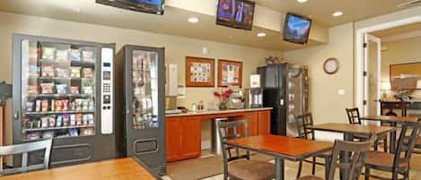A restaurant with tables, chairs, a counter, and vending machines.