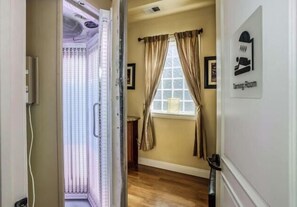 Une chambre d’hôtel dotée d’une grande fenêtre, d’une porte donnant sur un balcon et d’une pancarte indiquant « salle de bronzage ».