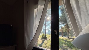 Una stanza con finestra, tende e vista su un giardino.