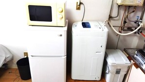 A compact kitchenette with a microwave, refrigerator, and washing machine. - Nisshou House (Sapporo)