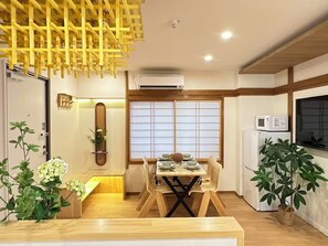 A modern kitchen with a wooden dining table, a refrigerator, and a microwave. - H302 *[New] Luxury Home in Tokyo | Japanese-style 2LDK | Honjo-Azumabashi Station & Direct Access to the Airport | Near Asakusa & Sky Tree (Sumida Ward)