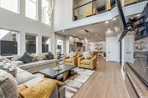 A spacious living area with a high ceiling, large windows, and a modern kitchen in the background. - Luxurious 5-Bedroom Home in the Heart of Dallas (Dallas)