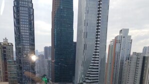 Un quartier urbain caractérisé par de nombreux immeubles de grande hauteur et une architecture moderne, notamment une tour remarquable et un grand bâtiment commercial doté d’un panneau publicitaire numérique bien visible.