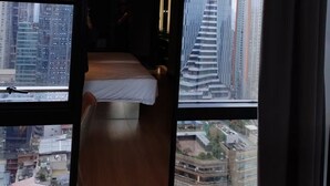 Une chambre d’hôtel avec un lit et une vue sur de hauts immeubles.