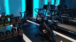 Une salle de sport équipée de matériel d’exercice, notamment des haltères, un vélo d’appartement et des tapis de course.