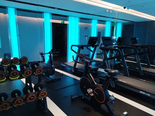 A gym with exercise equipment, including dumbbells, a stationary bike, and treadmills. - Chongqing Justom Hotel Branch 2 (Chongqing)