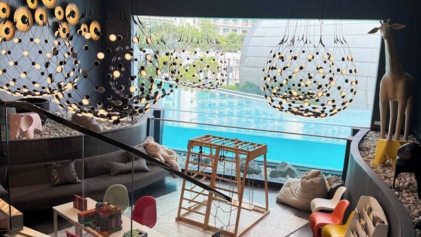 A modern living room with a pool view, a staircase, and a giraffe statue. - Hotel Residences at Acqua (Mandaluyong)