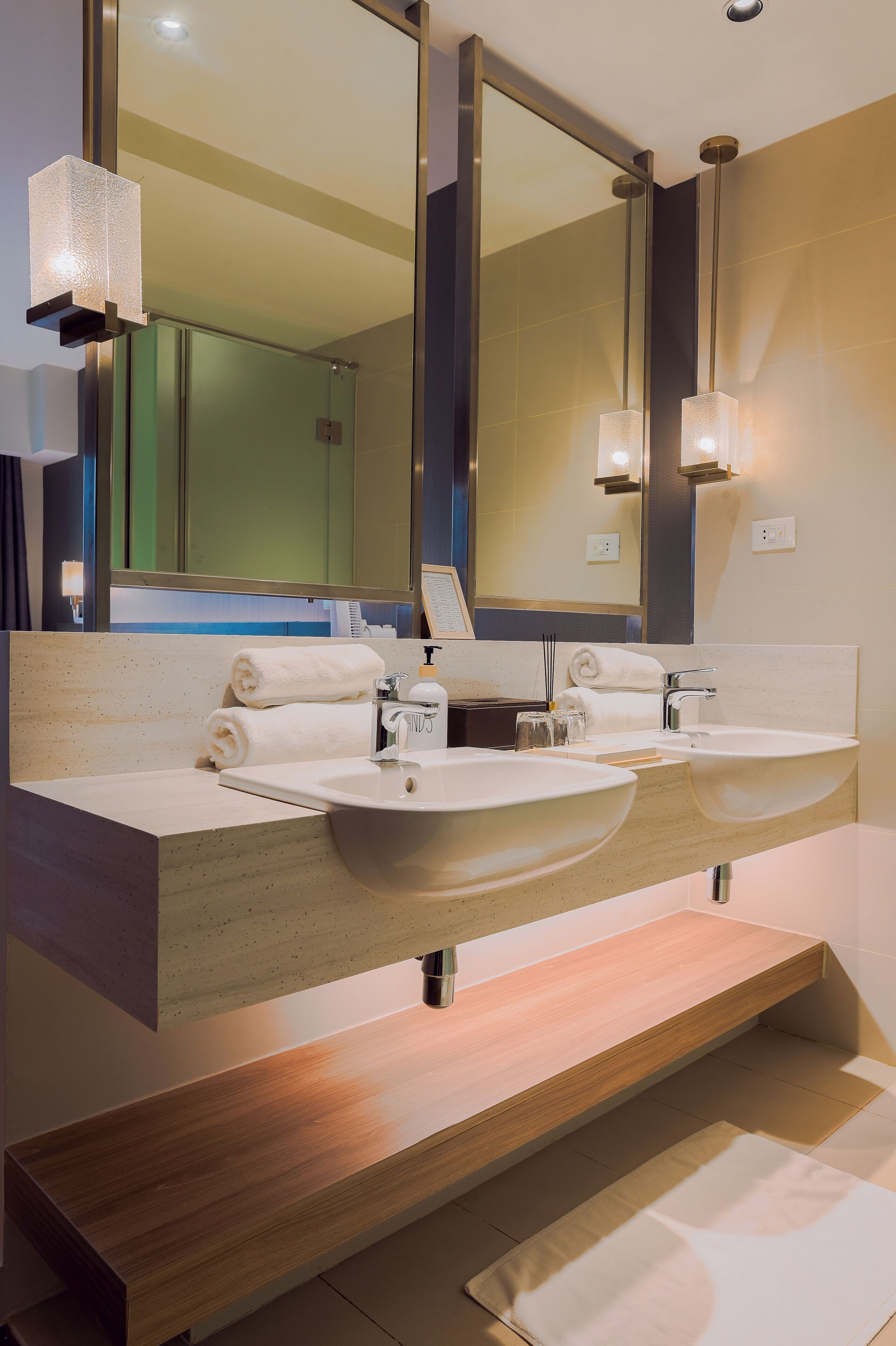Un baño moderno con dos lavamanos, un espejo grande y un mueble de tocador de madera.
