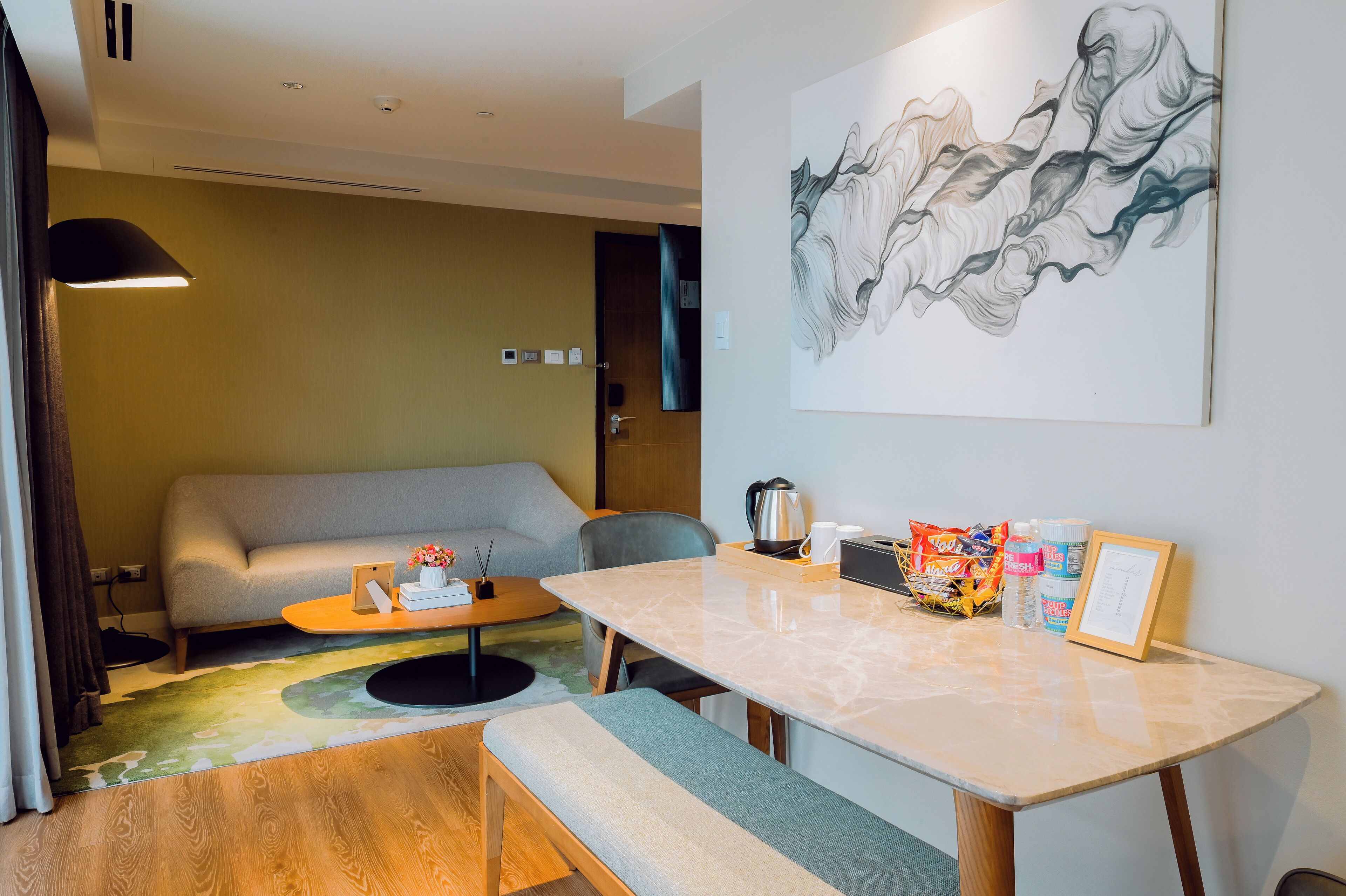 Ein modernes Hotelzimmer mit einer Couch, einem Esstisch, einem Couchtisch und einem Bild an der Wand.
