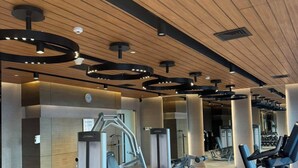 A modern gym with cardio equipment, weight machines, and a wooden ceiling. - Hotel Residences at Acqua (Mandaluyong)
