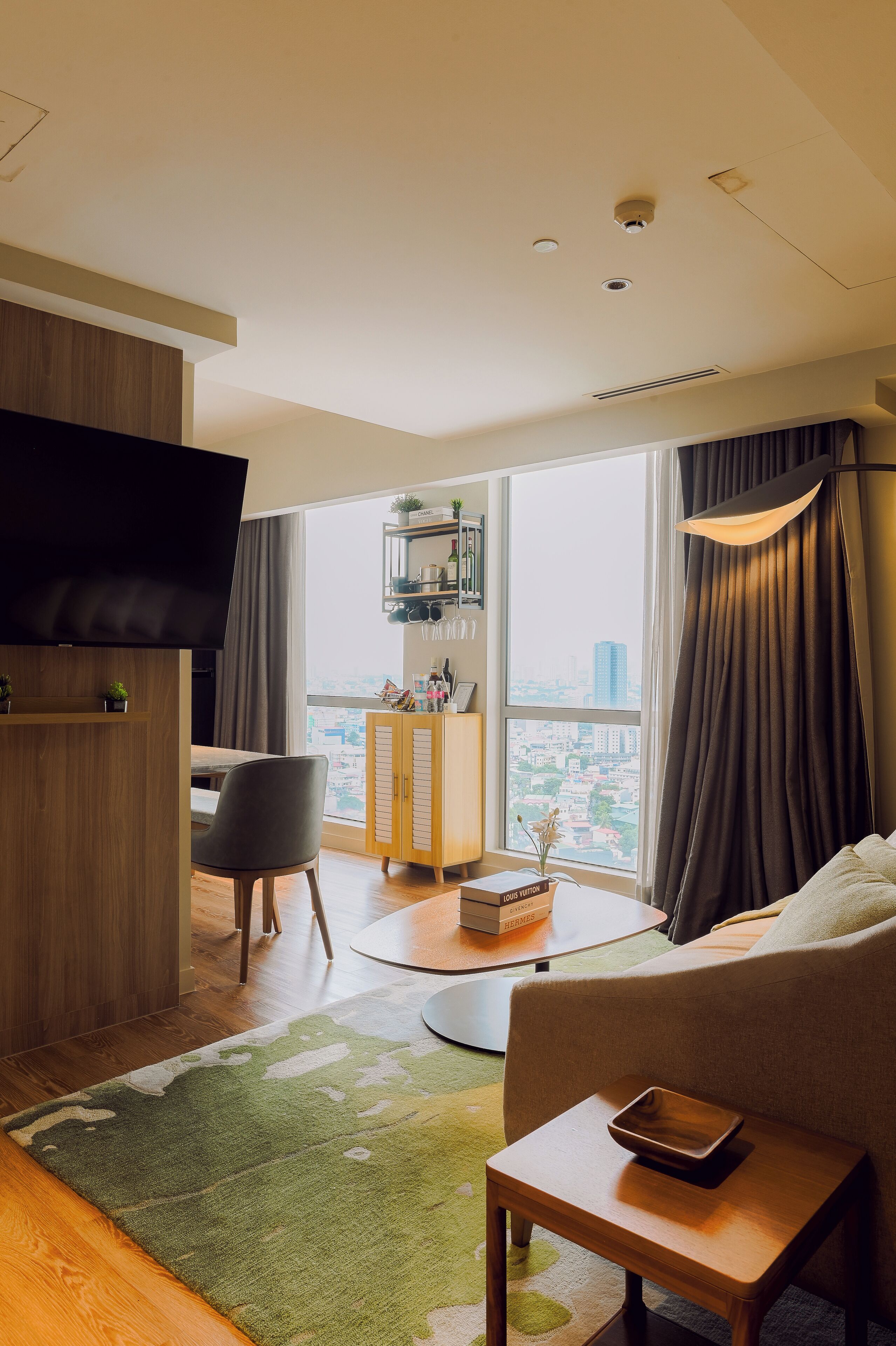 Ein modernes Wohnzimmer mit Flachbildfernseher, einer Couch, einem Essbereich und Blick auf die Stadt durch große Fenster.