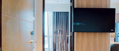 A hotel room with a wooden floor, a flat-screen TV mounted on the wall, and a door labeled "2817".
