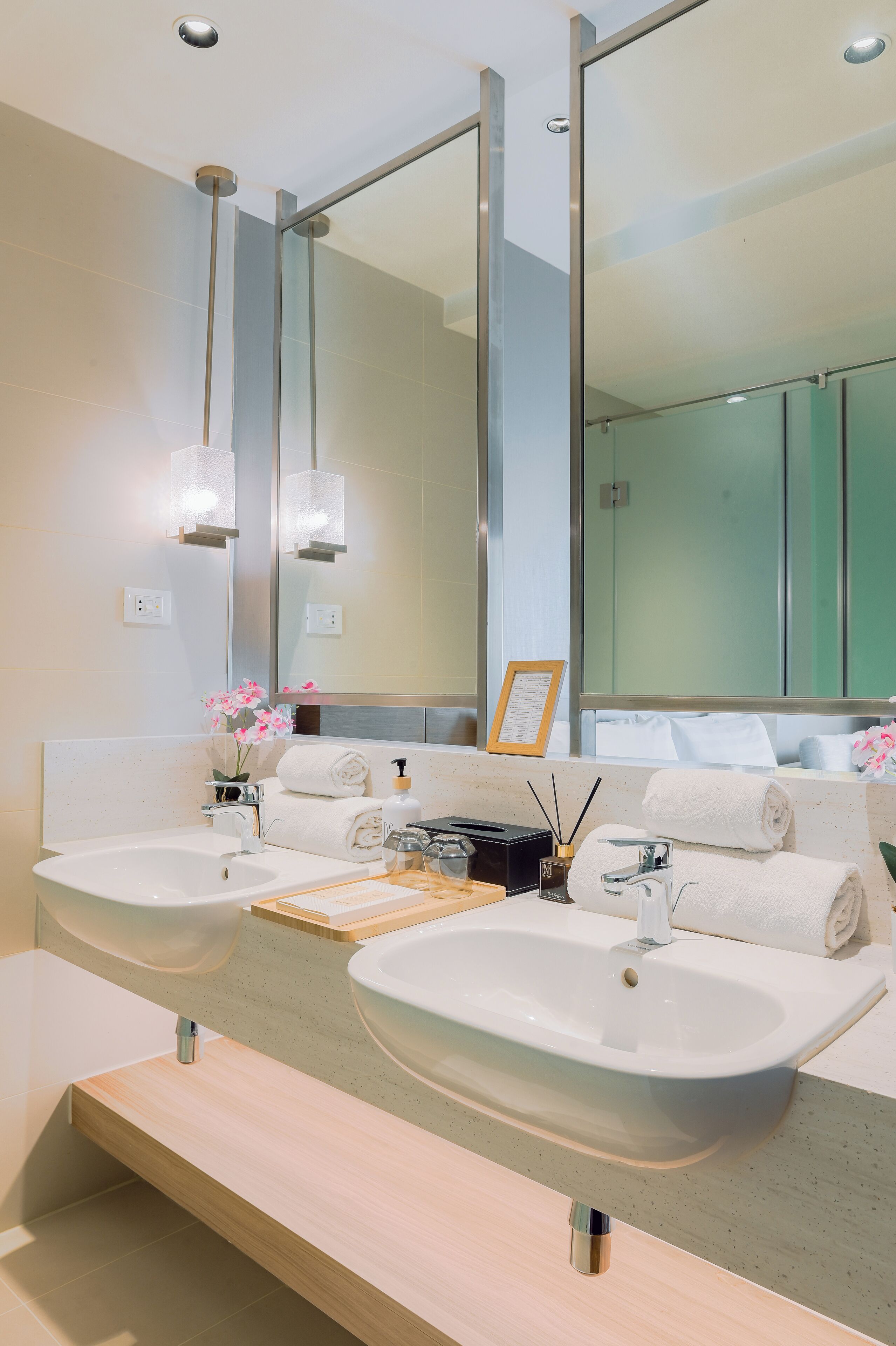 A modern bathroom with two sinks, a large mirror, and a wooden vanity.