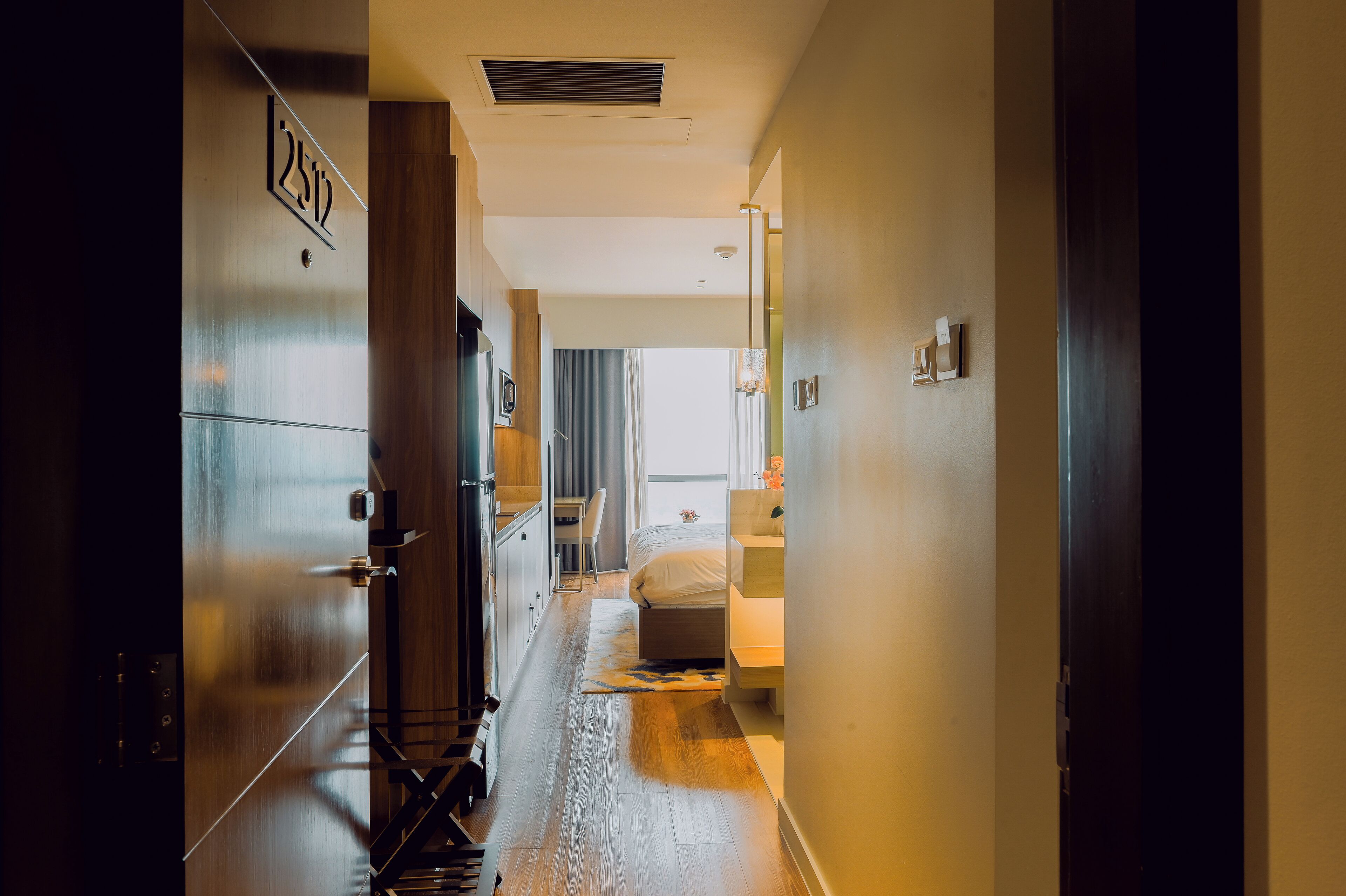 A hotel corridor with a bed, a desk, and a chair.