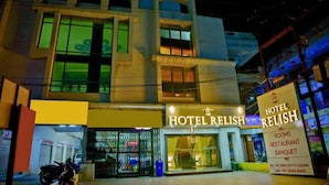Un hotel llamado HOTEL RELISH con un letrero que indica habitaciones, restaurante y servicios para banquetes.