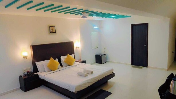 Un dormitorio moderno con una cama grande, lámparas de noche, una puerta oscura y un techo con detalles azules.