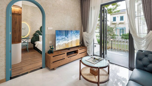 Ein modernes Wohnzimmer mit großem Fernseher, einer Holz-Unterhaltungsecke und einem Glastisch.