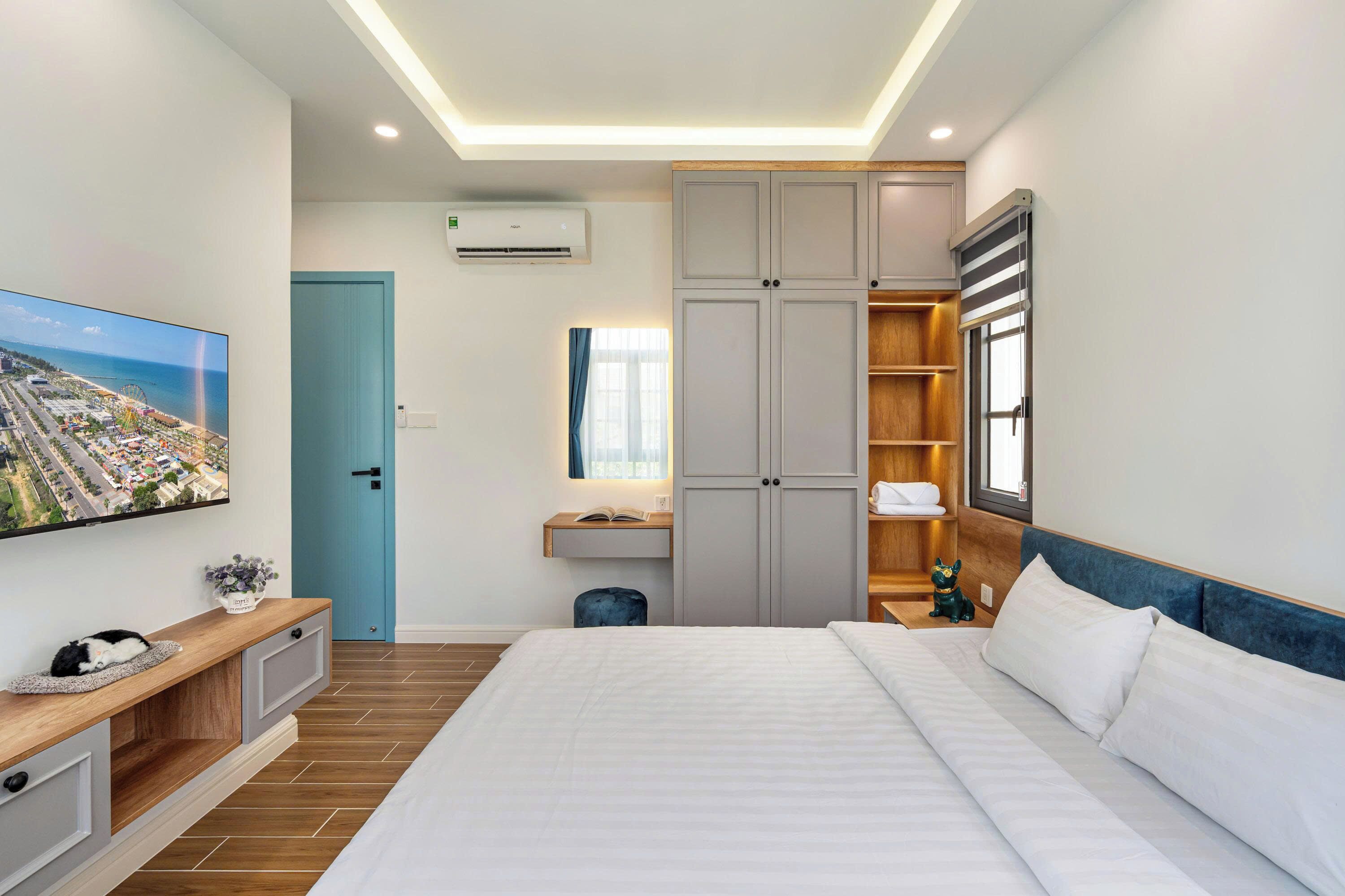 Een moderne hotelkamer met een groot bed, een flatscreen televisie, een kledingkast en een bureau met een lamp.
