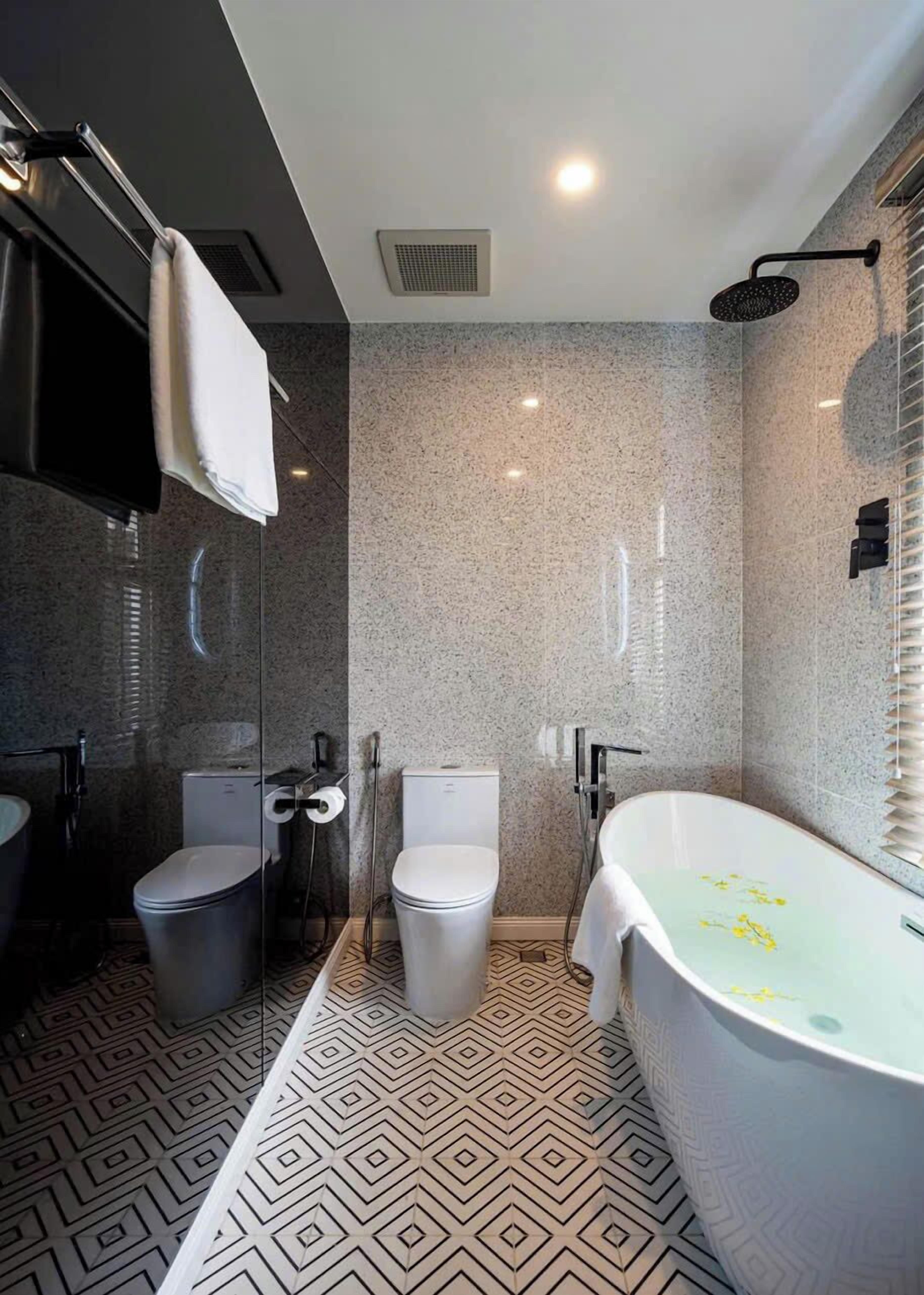 Ein modernes Badezimmer mit freistehender Badewanne, zwei Toiletten und einer Duschkabine.