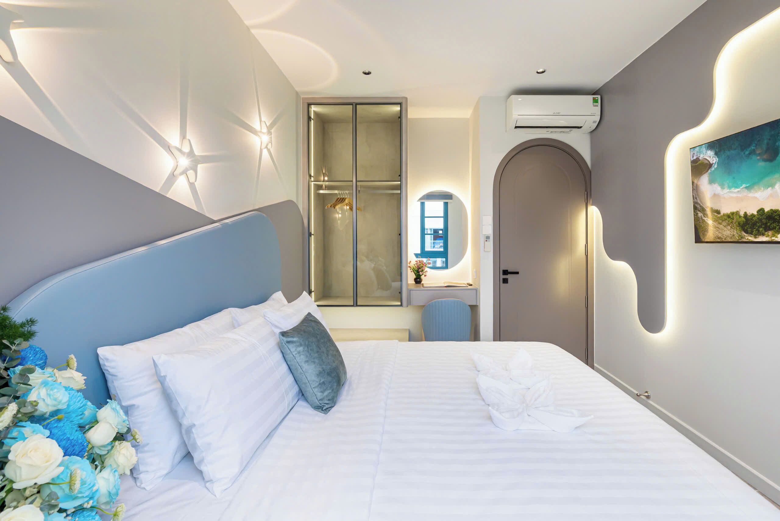 A modern hotel room with a large bed, a desk, and a walk-in closet.