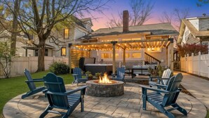 A backyard patio with a fire pit, outdoor seating, and a covered area with string lights. - Hot Tub | Firepit | Putting Green | 5 Bedrooms (Shelbyville)