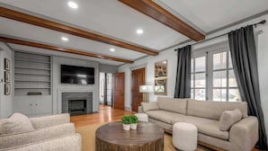 A living room with a fireplace, a sofa, a coffee table, and a television. - Hot Tub | Firepit | Putting Green | 5 Bedrooms (Shelbyville)
