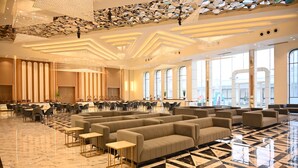 A spacious lobby with a modern design, featuring a large seating area with sofas and tables, a patterned floor, and large windows providing natural light. - The Hoften Lotus Court, Greater Noida (Greater Noida)