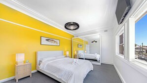 A hotel room with a bed, bedside tables, a mirror, and a window with a view. - MetaWiseBnB | Cozy 2Bed Earlwood Near City&Airport (Earlwood)