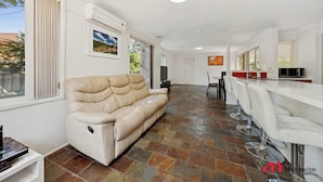 A modern living room with a sofa, a dining area with a bar, and a kitchen. - MetaWise Cozy Family Room4 in Shared Home Free Parking (Castle Hill)