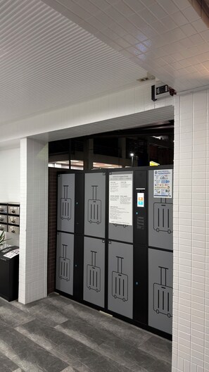 A self-service luggage storage area with numbered lockers and a digital information kiosk.