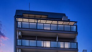 A multi-story building with a modern design, featuring balconies, large windows, and a ground-level entrance with signage. - Sidihome 365 Apartment (Osaka)