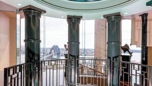 A high-ceilinged balcony with metal railings, large pillars, and a view of a cityscape including a bridge. - Fantastic city-view home in the Rocks (The Rocks)