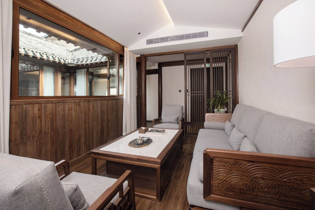 A traditional Japanese-style room with tatami flooring, a low wooden table, a sofa, and a sliding door leading to another room.
