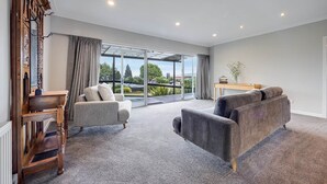 Ein geräumiges Wohnzimmer mit einer großen Schiebeglasdoor zum Balkon, einer Holzkommode, einem grauen Sofa und einem kleinen Tisch mit einer Vase.