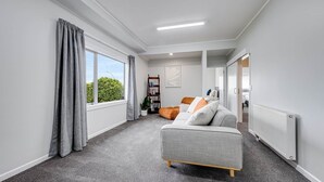 Ein modernes, gut beleuchtetes Zimmer mit einem grauen Sofa, einem Bücherregal und einer Heizung.