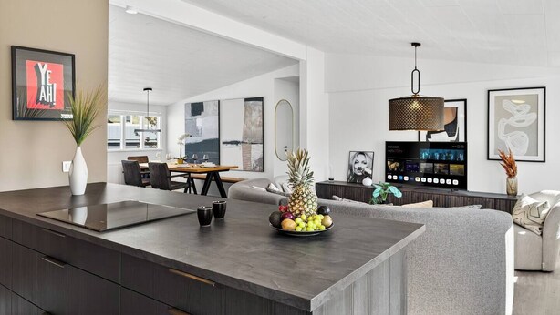 Una cocina moderna con una isla central, zona de comedor y sala de estar.