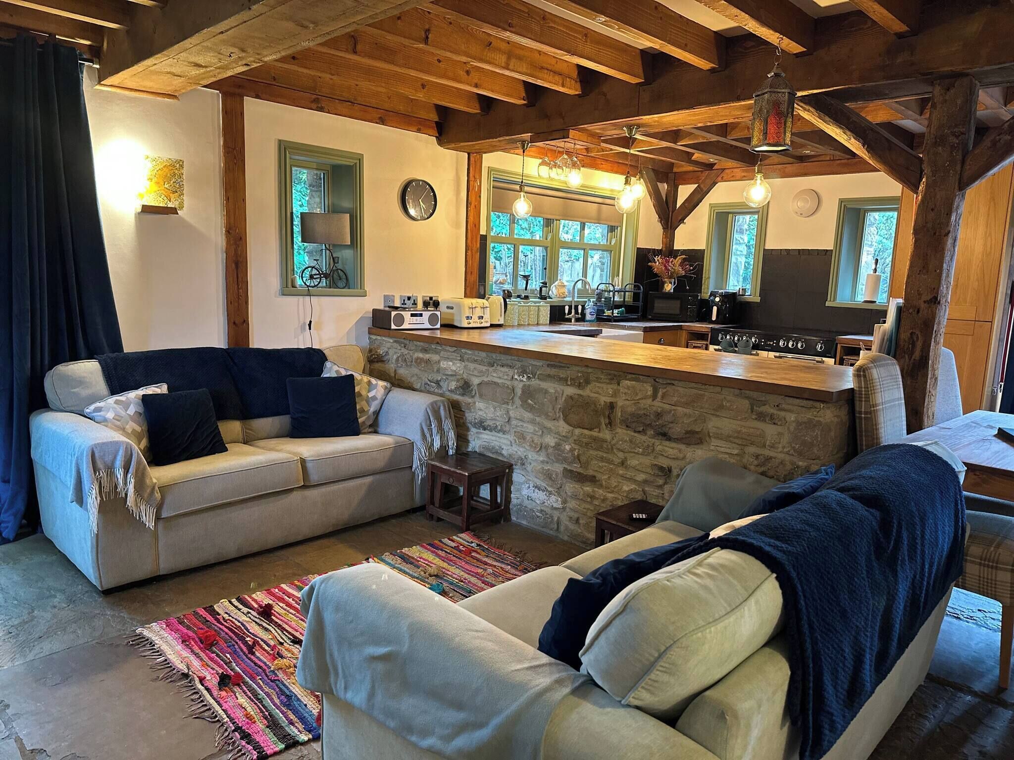 A cozy living room with a stone fireplace, a sofa, and a kitchen area with a wooden countertop.