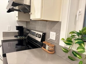 Una cocina moderna con estufa negra, electrodomésticos de acero inoxidable y encimera de mármol.
