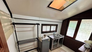 A compact kitchen with a sink, a small refrigerator, and a window with blinds. - Bansuan Banjong Akkson (Klaeng)